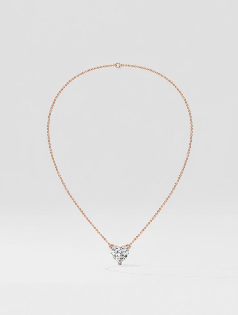 Rose gold necklace with a heart-shaped diamond pendant on a light gray background