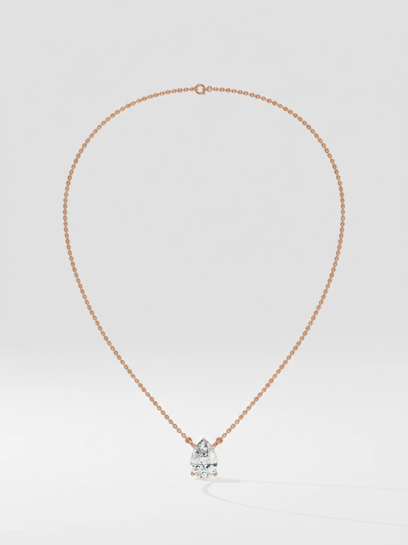Rose gold necklace with a pear cut diamond solitaire pendant on a light gray background