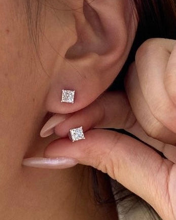 Close-up of a person wearing diamond stud earrings.