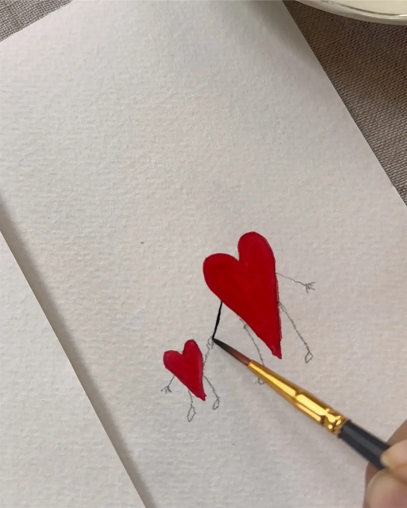 Red hearts being painted in watercolour