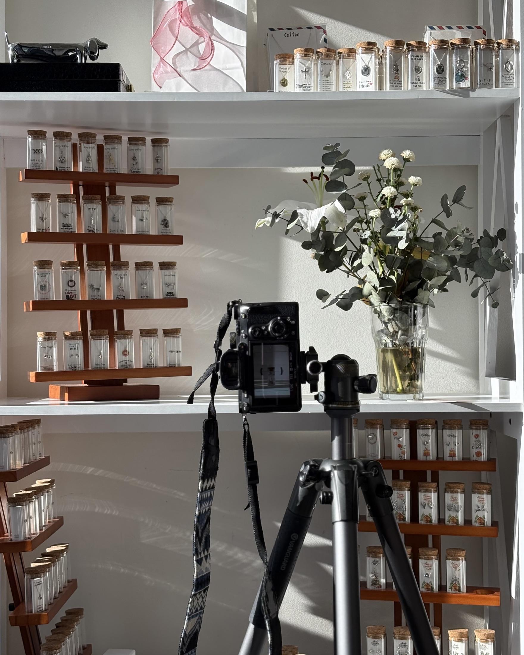 Shelves of ARKH bottles in the studio, with a camera on a tripod