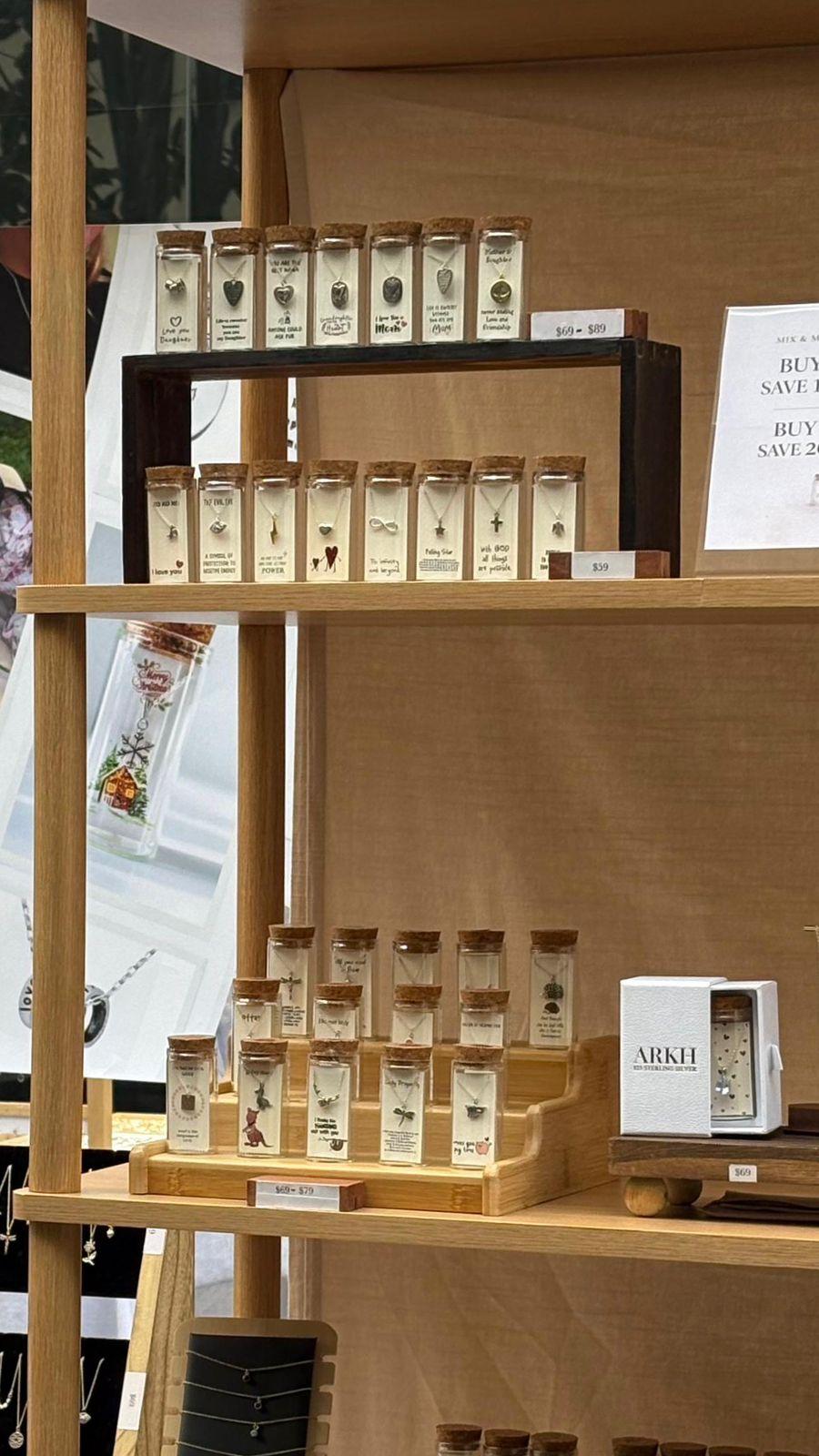 ARKH bottles ranked on wooden display stands at a market stall, with price cards