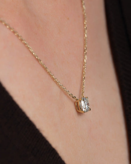 Side profile of custom cushion cut diamond necklace in gold highlighting setting and chain