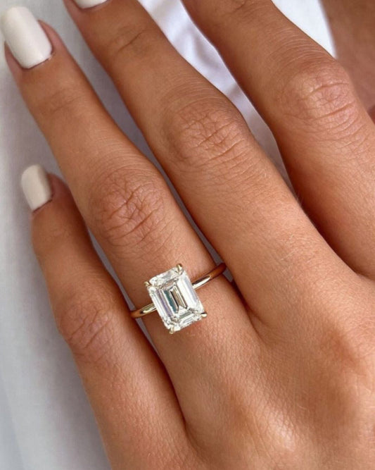 Emerald solitaire ring in gold worn on hand showing scale and sparkle