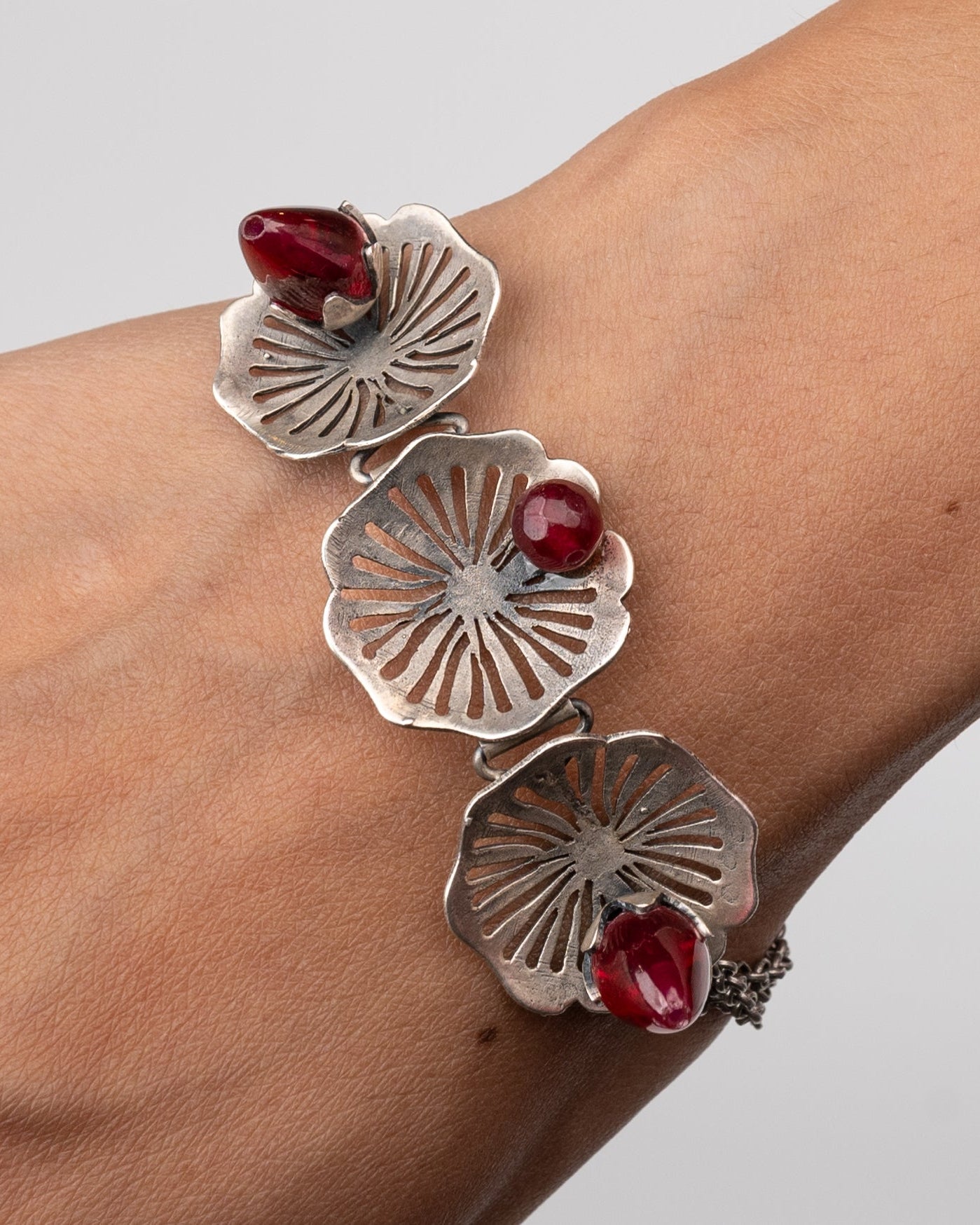 Silver bracelet with Pink stones on a wrist against a gray background