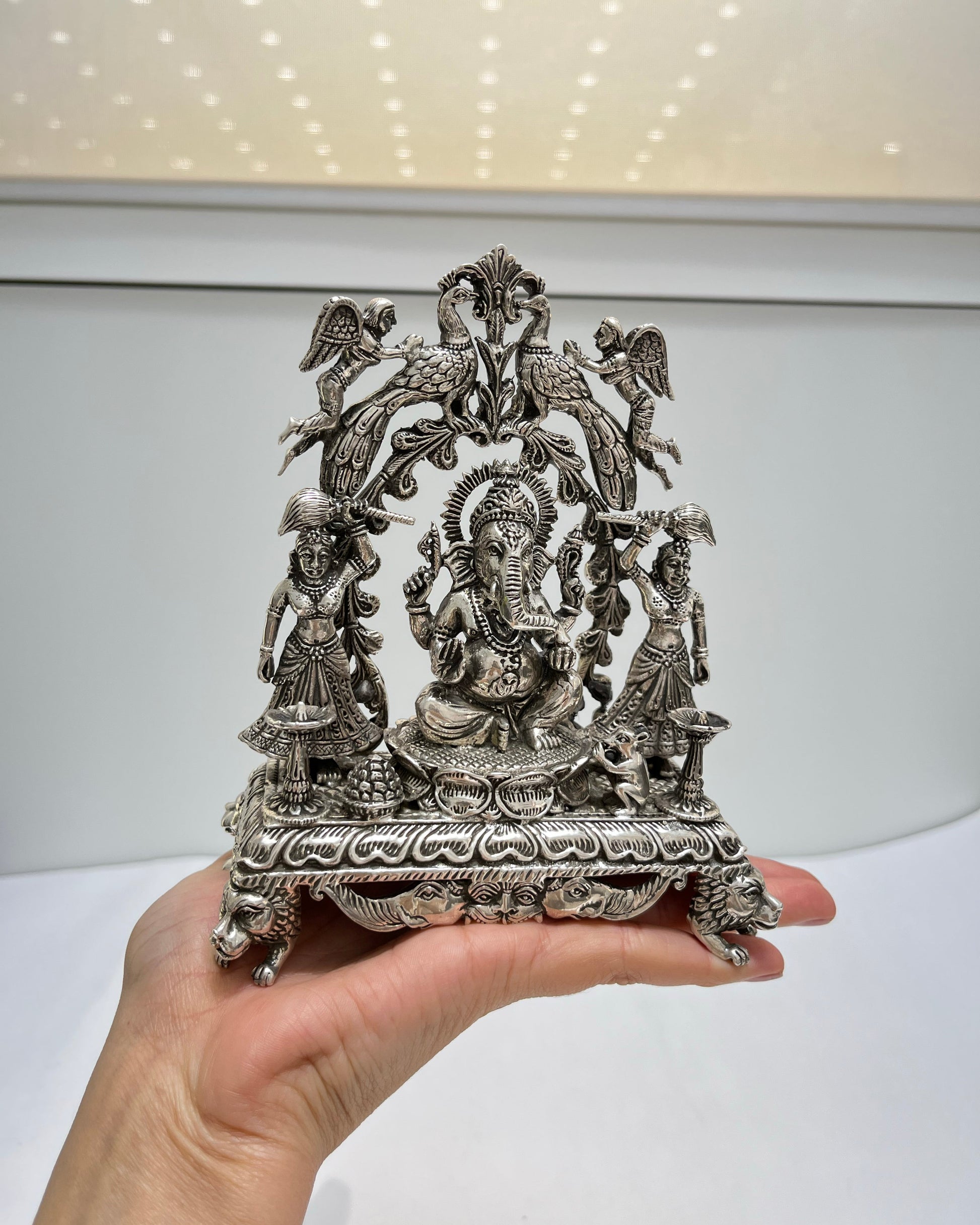 Decorative silver statue held in a hand against a white background
