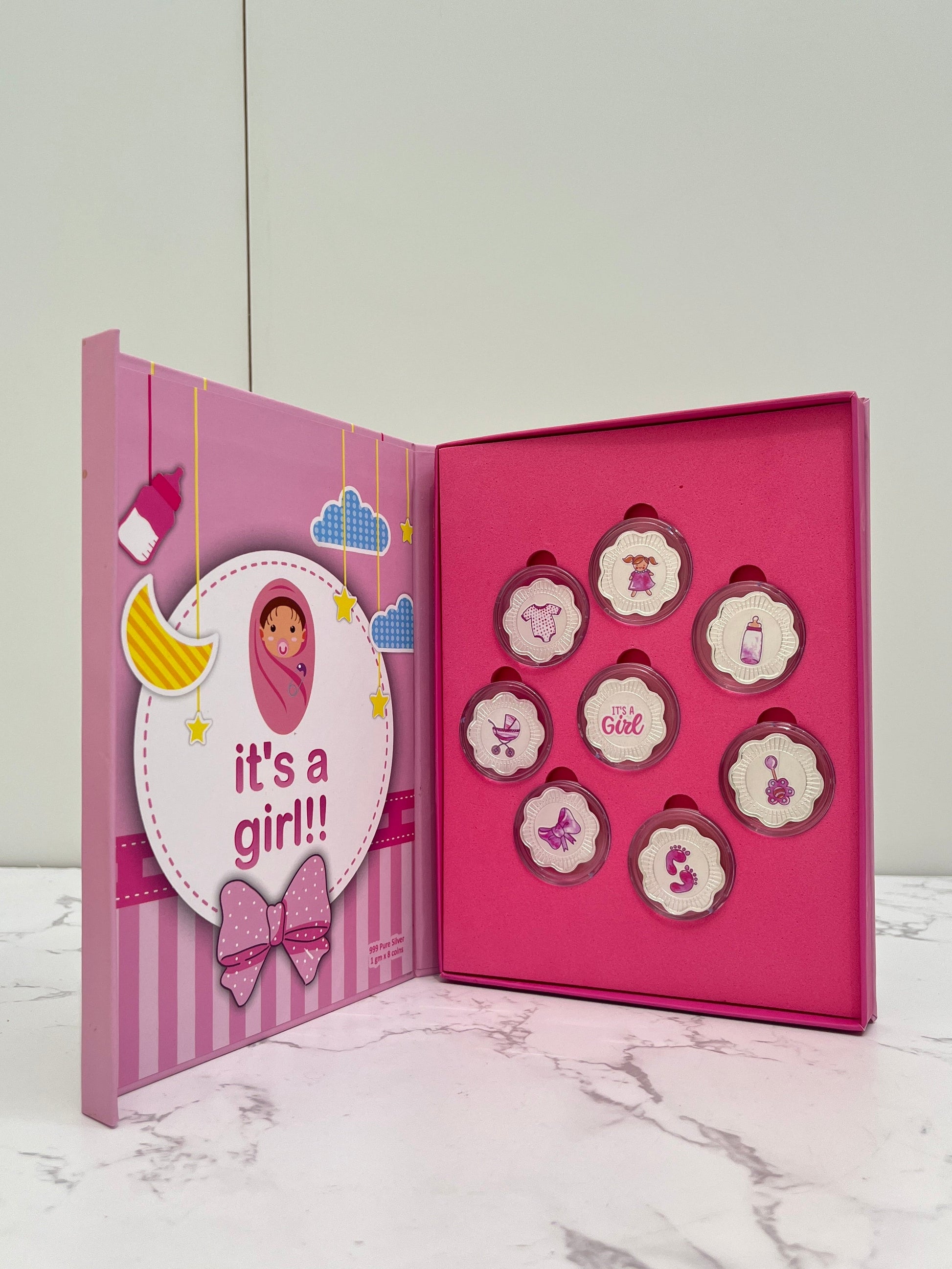 Pink baby shower favor box with decorative elements on a marble surface