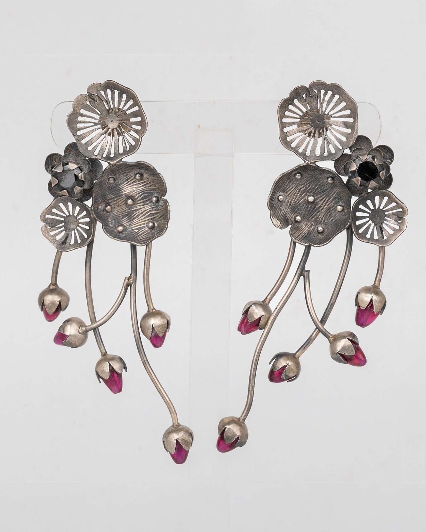 Pair of silver floral earrings with pink accents on a light gray background