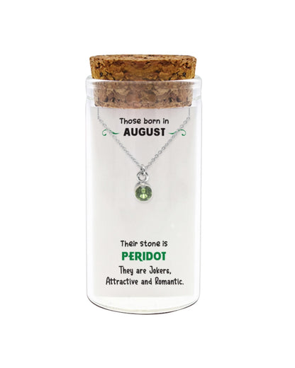Necklace with a peridot gemstone in a glass jar with cork lid on a white background