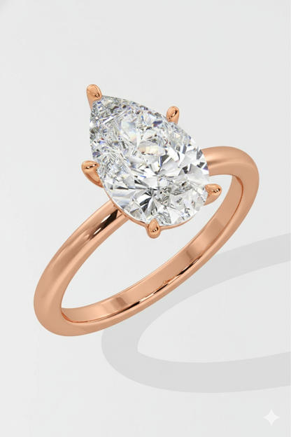 Rose gold ring with a pear-shaped diamond on a light gray background