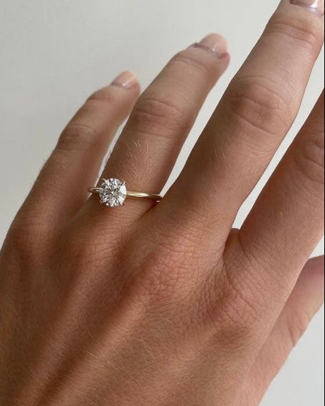 Hand wearing Round solitaire ring in gold with lab-grown diamond showing scale and sparkle