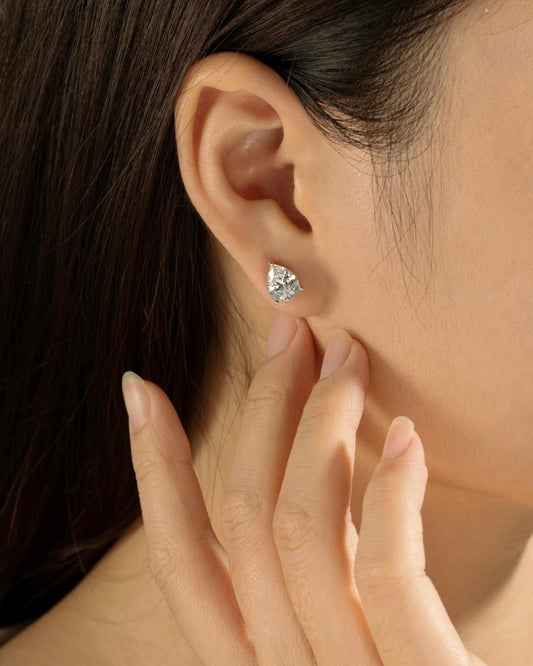 Close-up of pear solitaire earring worn on ear – elegant gold pear diamond studs